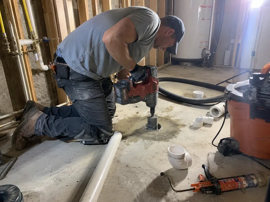 Technician installing radon mitigation suction point in Pueblo basement